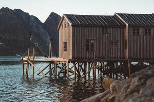 velhas casas de pesca de madeira perto do lago contra o fundo das montanhas foto