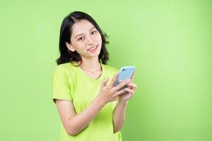 imagem de jovem asiática segurando um smartphone sobre fundo verde foto