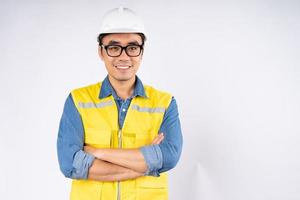sorridente jovem engenheiro civil asiático usando capacete de proteção em pé sobre fundo branco isolado. conceito de serviço mecânico. foto