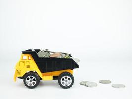 caminhão de brinquedo com moedas no fundo branco, conceito de negócio foto
