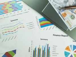 gráfico de relatório de negócios e análise de gráfico financeiro com dinheiro em dólares e caneta na mesa foto
