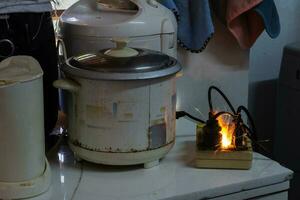 elétrico curto, plugue, arroz fogão Portanto causando faíscas perigoso conceitos a partir de a usar do velho elétrico eletrodomésticos e sem qualidade Portanto é perigoso para vida e propriedade foto