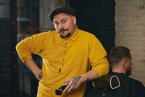 barbeiro fazendo corte de cabelo de atraente homem barbudo na barbearia foto