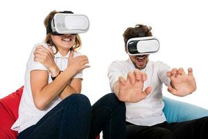 animado jovem casal experimentando virtual realidade sentado em pufes isolado em branco fundo foto
