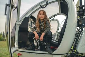 confiante pré-adolescente menina dentro camo estilo blusa sentado dentro aberto helicóptero foto