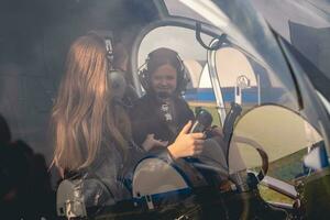 alegre pré-adolescente meninas dentro fones de ouvido falando dentro helicóptero cockpit foto