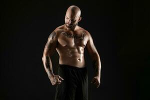 Atlético Careca, barbudo, tatuado homem dentro Preto calção é posando contra uma Preto fundo. fechar-se retrato. foto