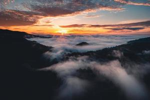 o sol nasce na névoa e as montanhas pela manhã foto