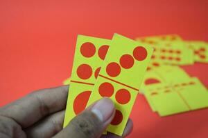 mão aguarde dominó jogando cartões isolado vermelho fundo, amarelo vermelho dominó cartões foto