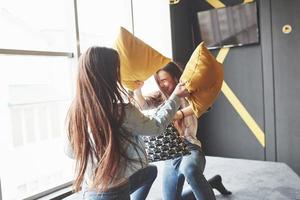 duas lindas irmãs gêmeas passando um tempo juntas lutando com travesseiros. irmãos se divertindo em casa conceito foto