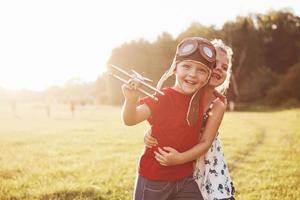 irmão e irmã estão brincando juntos. duas crianças brincando com um avião de madeira ao ar livre foto