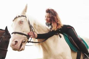 linda jovem abraçando seu cavalo enquanto está montado. ela gosta de animais foto