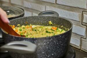 chefe de cozinha cozinhando delicioso cuscuz sopa com fresco verduras em gás fogão foto