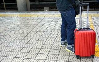 fechar-se pernas do turista homem com pequeno vermelho bagagem esperando para a Japão metrô para a aeroporto às numba metrô estação. foto