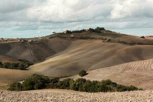 colhido Campos e prados panorama dentro toscana, Itália. ondulado país cenário às outono pôr do sol. arável terra pronto para a agrícola temporada. foto