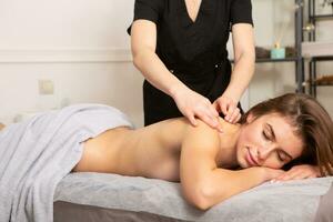 jovem mulher obtendo uma costas massagem dentro uma spa salão. beleza tratamento conceito. foto