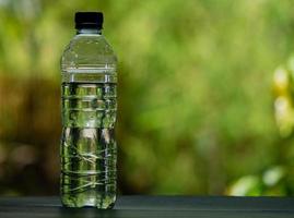 garrafa de água potável em branco sobre fundo verde desfocado foto