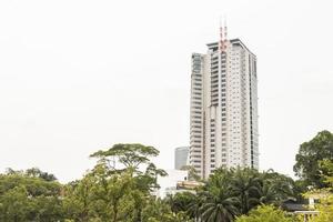 ao fundo, um edifício alto arranha-céu perdana jardins botânicos. foto