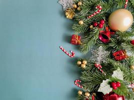 decorações de natal, folhas de pinheiro, bolas douradas, flocos de neve, bagas vermelhas e bagas douradas sobre fundo azul foto