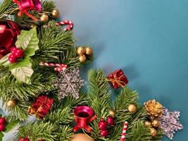 decorações de natal, folhas de pinheiro, bolas douradas, flocos de neve, bagas vermelhas e bagas douradas sobre fundo azul foto