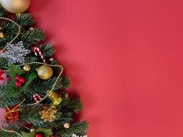 decorações de natal, folhas de pinheiro, bolas douradas, flocos de neve, bagas douradas e bagas vermelhas sobre fundo vermelho foto