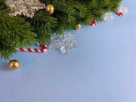 decorações de natal, folhas de pinheiro, bolas douradas, flocos de neve, bagas douradas sobre fundo azul foto