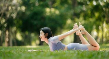 retrato do jovem mulher praticando ioga dentro jardim.fêmea felicidade. dentro a parque borrado fundo. foto