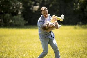 pai com filha se divertindo na grama do parque foto