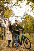 jovem casal no parque outono com bicicleta elétrica