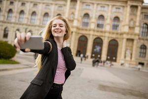 jovem turista feminina tirando selfie com foto móvel no centro de Viena, Áustria