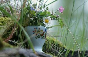 uma vaso com flores sentado em topo do uma Rocha foto