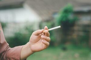 uma fumar homem é segurando cigarro em dele mão foto