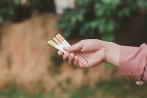 uma fumante é segurando alguns cigarro em a mão foto