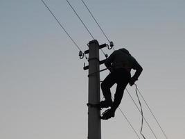 eletricista trabalha com roupas especiais no poste foto