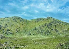 montanha panorama com verde grama, azul céu e branco nuvens fundo foto papel de parede