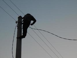 eletricista trabalha com roupas especiais no poste foto