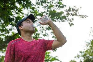 jovem corredor de aptidão homem bebendo garrafa de água. foto