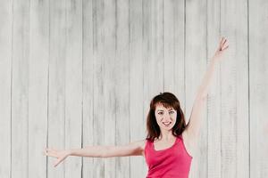 garota sorridente com um top esporte rosa, fazendo exercícios com as mãos foto