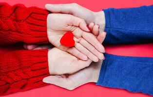 fêmeas e machos mãos detém vermelho coração em vermelho fundo. fechar-se. topo visualizar. foto