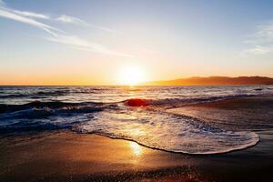 pôr do sol em a de praia refletindo dentro a oceano foto