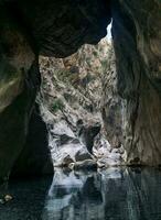 natural túnel dentro uma desfiladeiro com uma limpar \ limpo transparente rio foto