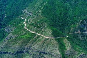 enrolamento estrada ao longo uma arborizado lado da montanha dentro uma terras altas terreno foto