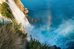 arco Iris às a pé do uma cascata queda para dentro a mar a partir de uma penhasco, mais baixo cara, Antalya foto