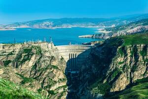 montanha panorama com a arqueado hidroelétrica barragem e uma reservatório dentro a desfiladeiro foto