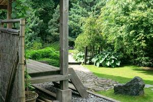 panorama do uma tradicional japonês jardim com plantas, caminhos e uma fragmento do uma pavilhão foto