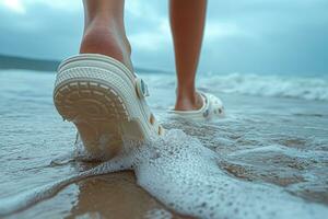 ai gerado crocs calçado pés do a pessoa em a de praia caminhando ao longo a surfar foto