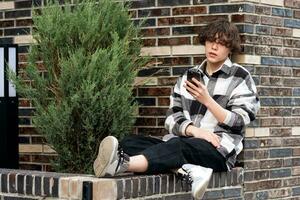 jovem homem lê alguma coisa em a telefone enquanto sentado dentro a parque foto