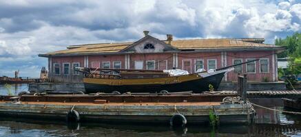 velho de madeira cais, uma Navegando navio é ancorado Próximo para uma flutuando cais casa flutuante foto