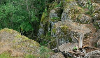 quebrado de madeira Escadaria em a abandonado caminho dentro uma montanha floresta foto