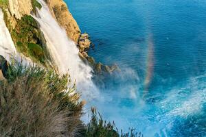 arco Iris às a pé do uma cascata queda para dentro a mar a partir de uma penhasco, mais baixo cara, Antalya foto